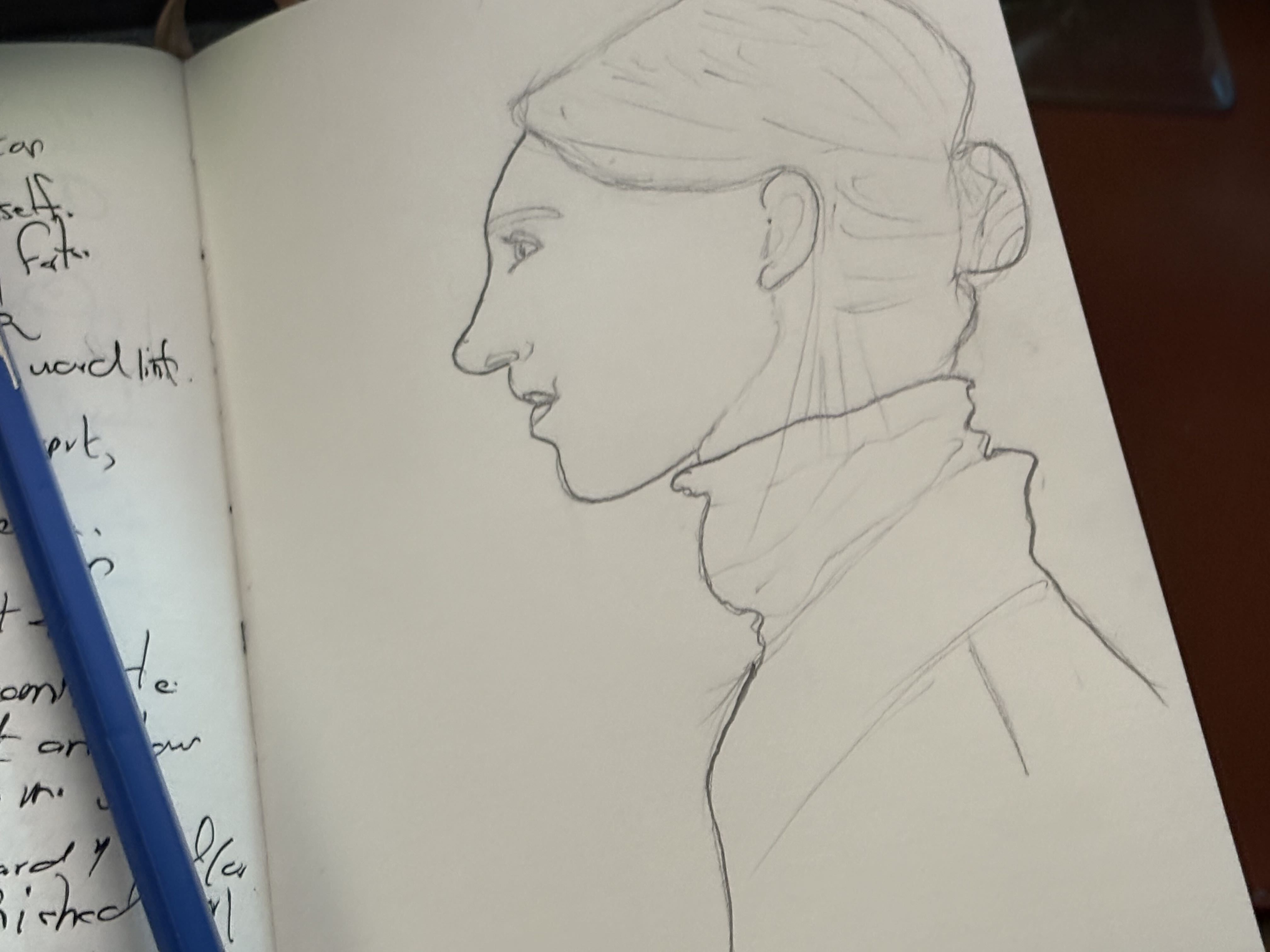 A pencil sketch of a woman in profile in a notebook